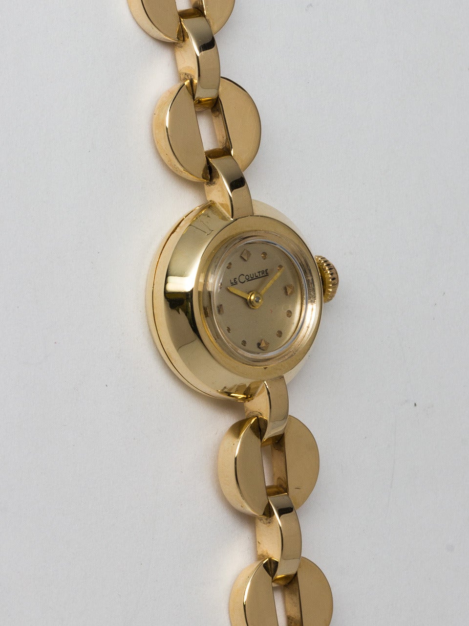 LeCoultre 14K Yellow Gold Lady's Dress Wristwatch circa 1940s. 18mm diameter dome shaped stepped case. Silvered dial with applied gold indexes and hands. Powered by 17 jewel manual wind movement. With yellow gold round disk shaped links and black