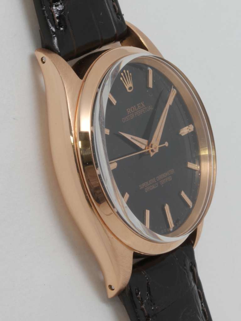 Rolex 18k rose gold Oyster Perpetual wristwatch, Ref. 1002, serial number 645,XXX, circa 1961. 34mm with smooth bezel, acrylic crystal and beautifully restored glossy black dial with applied pink indexes and pink dauphine hands. Self-winding calibre