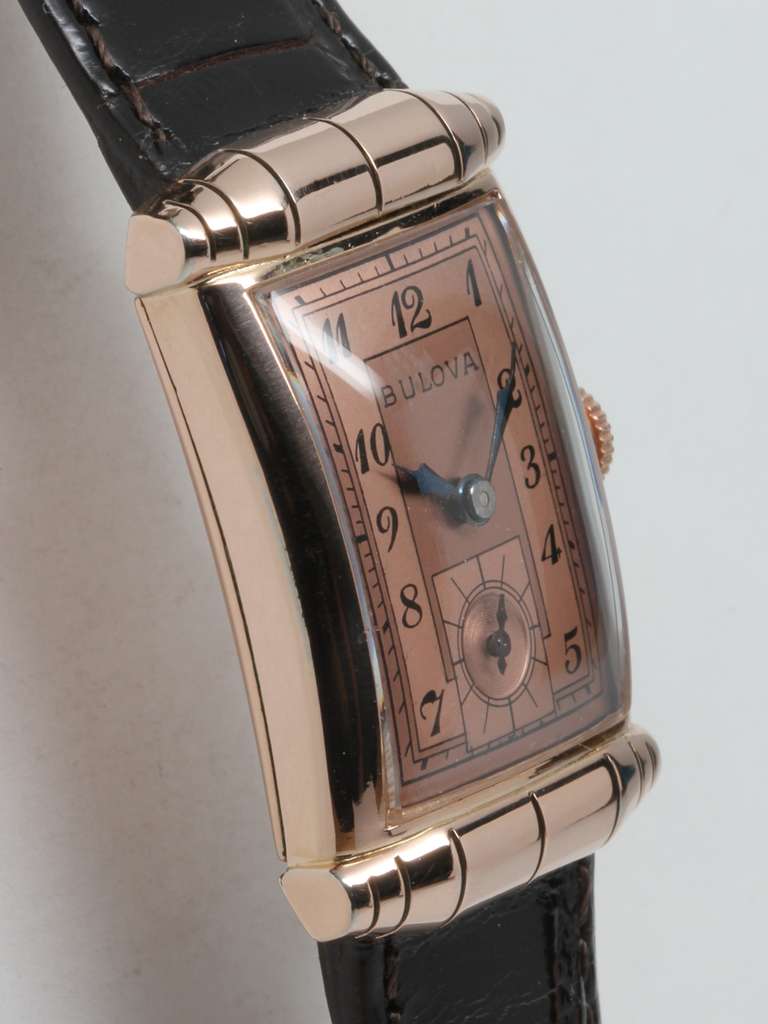 Bulova rose gold-filled rectangular wristwatch with barrel lugs, circa 1940s. 21 X 33mm. Beautiful two-tone salmon dial with black Arabic numerals. 17-jewel manual-wind movement with subsidiary seconds. Offered on your choice of leather or metal