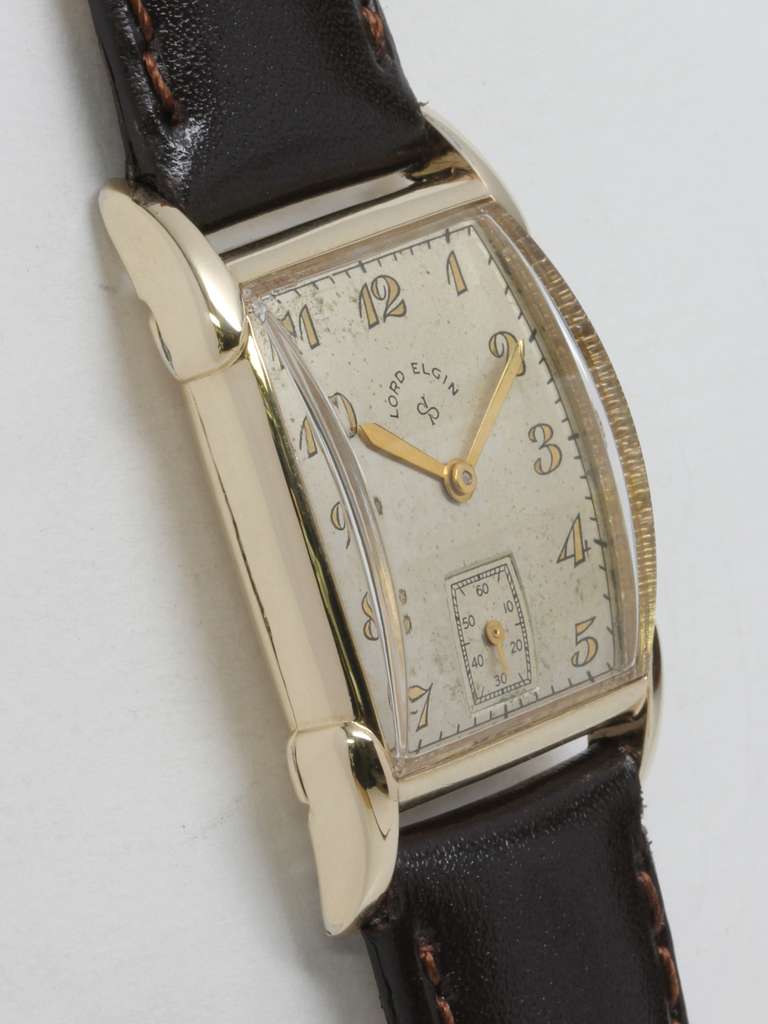 Elgin yellow gold-filled tonneau wristwatch, circa 1940s. 23 X 37 mm case with curved lugs. Original lightly patinaed silvered dial with Arabic numerals and baton hands. Powered by a 17-jewel manual-wind movement with subsidiary seconds. With your