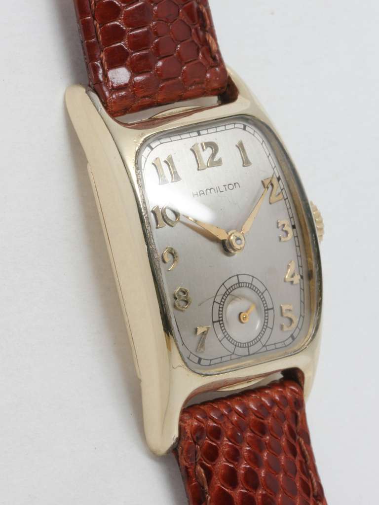 Hamilton yellow gold-filled Boulton tonneau wristwatch. This case classic model had one of the longest productions of all Hamilton wristwatches, from 1938 until 1951. Contoured 23 X 37mm case, silvered satin dial with applied Arabic numerals.