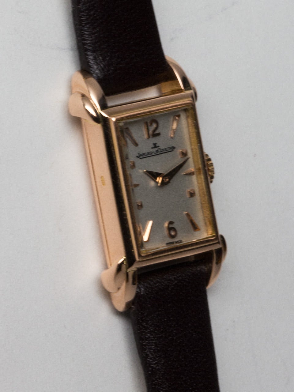 Jaeger LeCoultre 18K Rose Gold Lady's Dress Wristwatch circa 1950s. Rectangular case measuring 15 x 29.5mm with prominent stepped horn lugs. Featuring beautifully restored matte silvered dial with applied pink triangular indexes and tapered sword