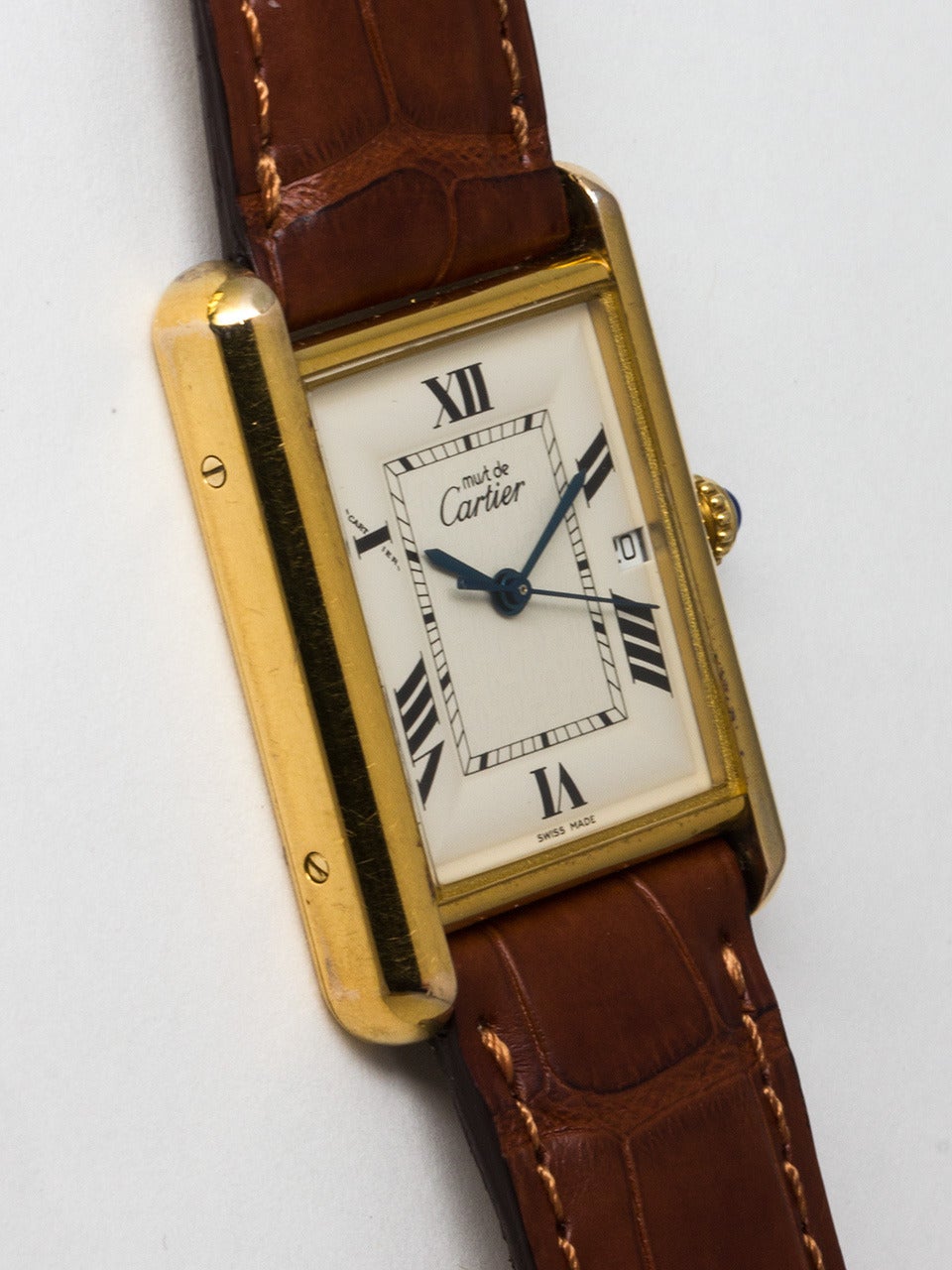 Cartier Man's Vermeil Tank Louis Must de Cartier Wristwatch, circa 2000s. Vermeil, 20 microns gold over silver, larger size 26 x 34mm water resistant style case secured by 8 case back screws and blue cabochon sapphire crown. Off white dial signed