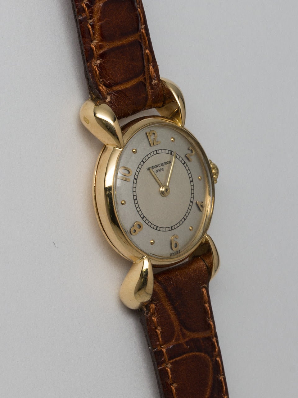 Vacheron & Constantin 18K Yellow Gold Lady's Dress Model Wristwatch, circa 1950's. 21 x 38mm case with large and dramatic lobed lugs, mushroom style V & C crown. Very pleasing 2 tone silvered satin dial with raised gold indexes and gold leaf hands.