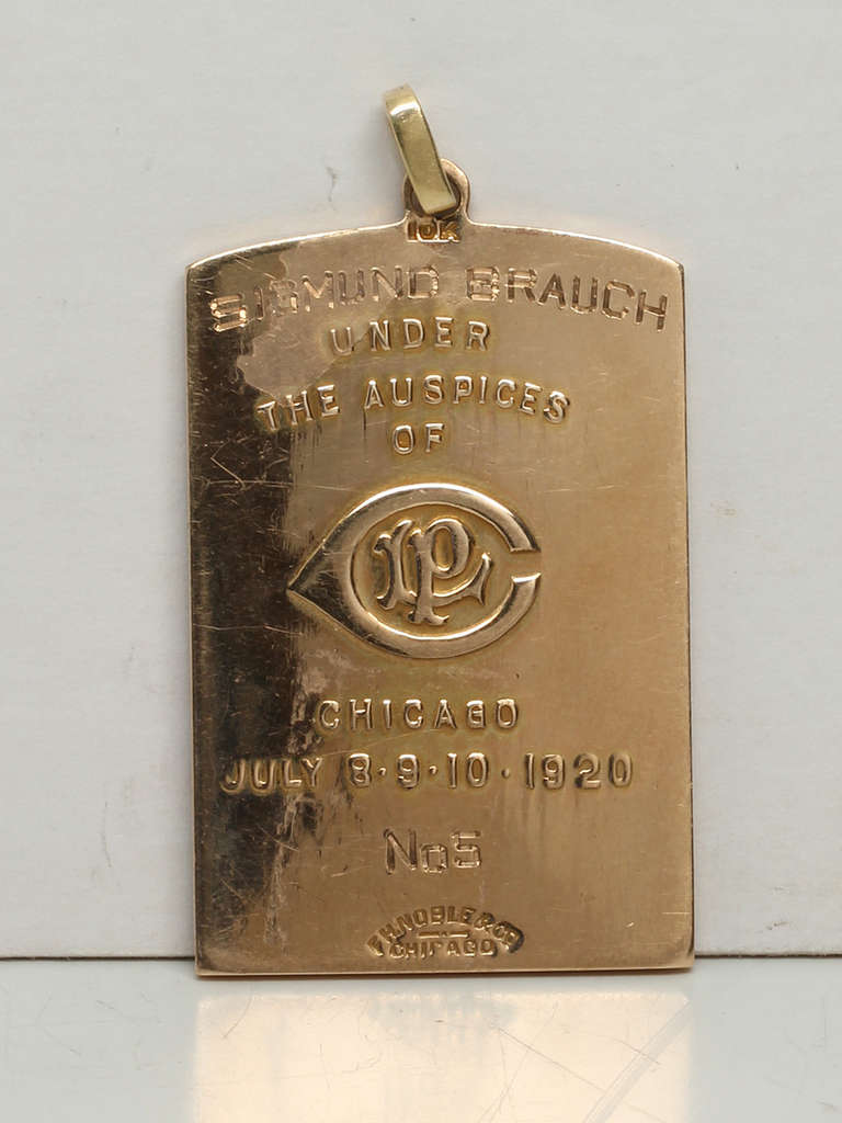 This vintage 10K  gold pendant is an awards plaque medal from the Central Association Regatta, an annual regatta hosted by the Central States Amateur Rowing Association on Lake Michigan, Chicago. The front of the pendant has an engraved figure of a