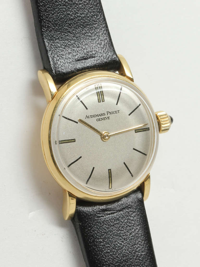 Audemars Piguet lady's 18k yellow gold wristwatch, Ref. 26129, circa 1960s. Case measuring 20 x 23 mm with extended lugs and cabochon sapphire crown. Featuring silvered dial with baton indexes and gold baton hands. Powered by a 17-jewel manual-wind