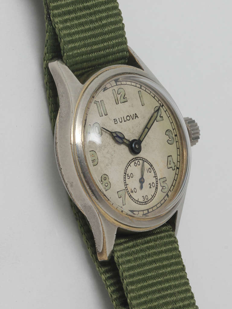 Bulova base metal military-style wristwatch, circa 1940s. 30 x 37mm diameter case with smooth bezel and acrylic crystal. Original silvered dial with patinaed luminous Arabic numerals and hands. Powered by manual-wind movement with subsidiary