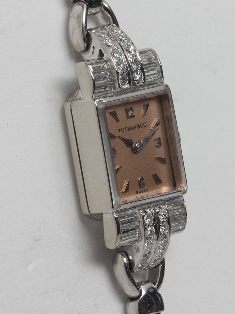 Tiffany and Co. lady's 14k white gold and diamond bracelet watch, circa 1950s. 12 x 28mm rectangular case with baguette diamond lugs. Lovely restored salmon dial with applied Arabic and dagger indexes and alpha hands. Powered by a Movado manual-wind