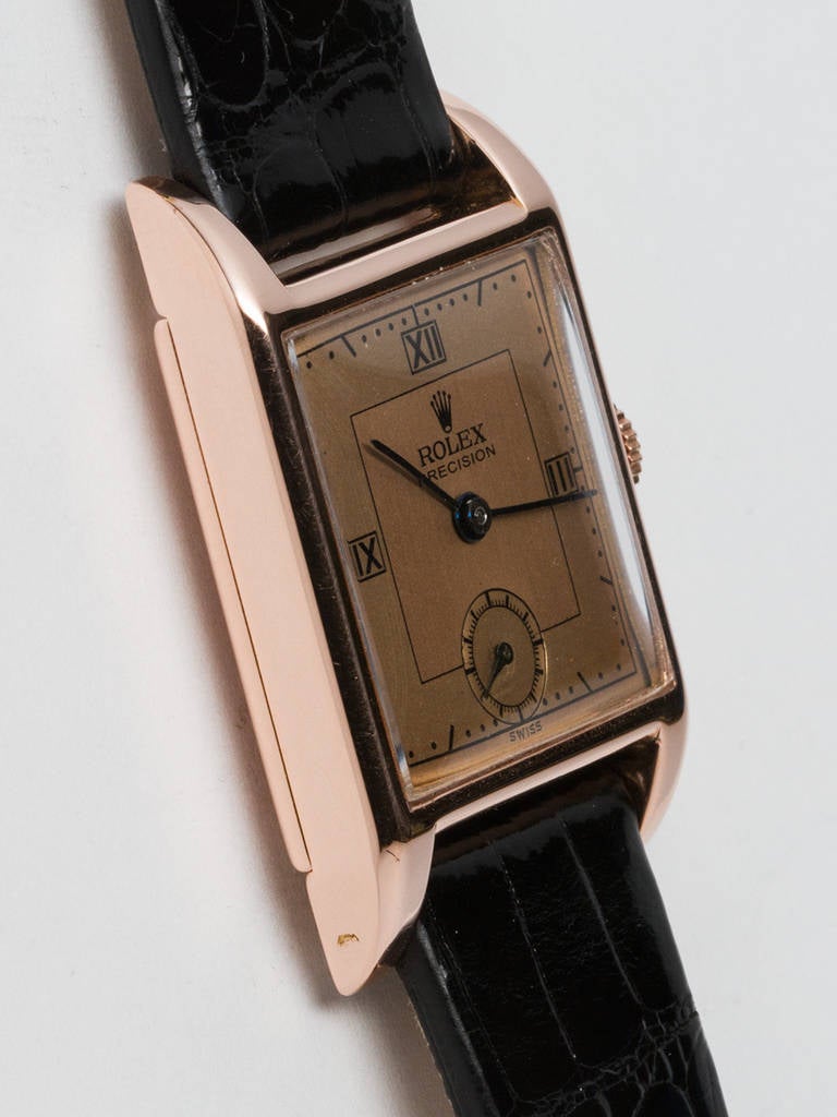 Rolex 14k rose gold Precision square wristwatch, circa 1944. 26 x 38mm square case with glass crystal. Lovely rose dial with printed black Roman numerals and blued steeled hands. Manual-wind movement with subsidiary seconds. Personalized engraving