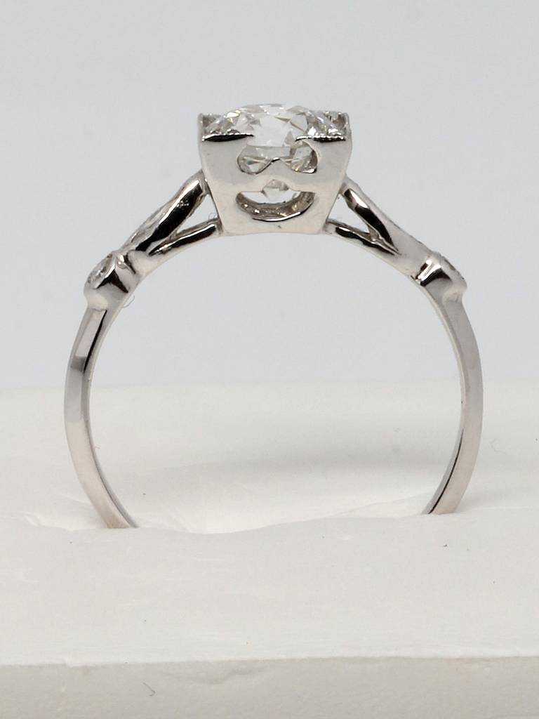 This delicately crafted 1930s vintage platinum engagement ring features an EGL certified colorless 1.04ct Old European cut center diamond, F-VS2, in an elevated square illusion setting with open side galleries. Two marquise and two round side