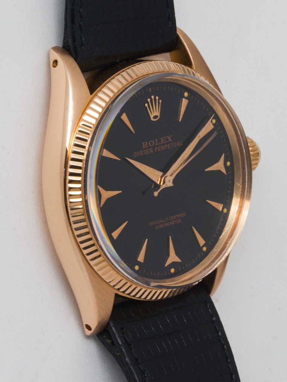 Rolex 18K rose gold Oyster Perpetual wristwatch, Ref. 6567, serial number 167,XXX, circa 1956. 34 mm man's model with fluted bezel and acrylic crystal. Black dial with applied faceted dagger indexes and dauphine hands. Powered by a self-winding