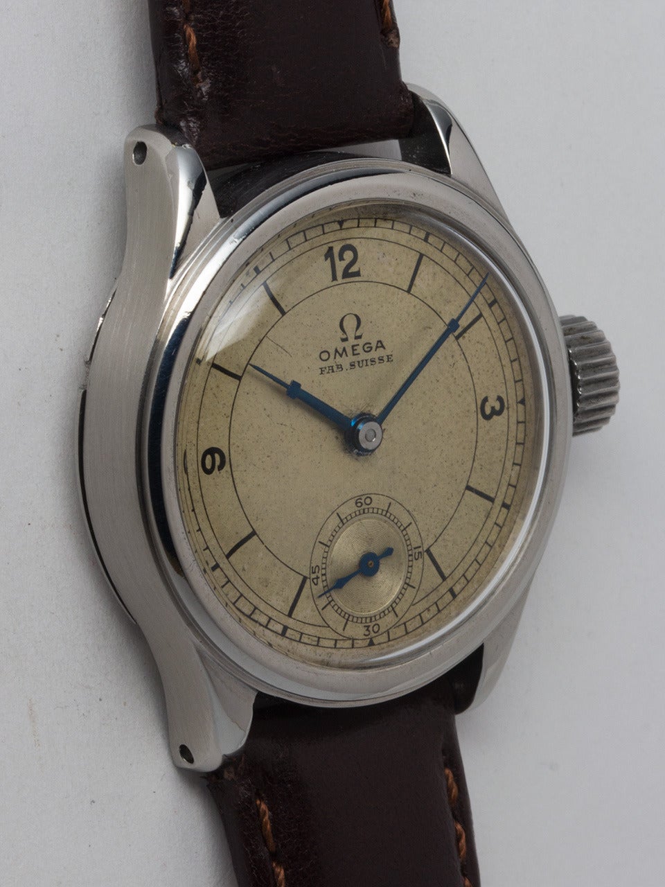 Omega stainless steel medium-size military-style wristwatch, circa 1942. 31 X 36mm case with wide bezel and oversized crown. With very pleasing original patina'd dial with black numerals. Powered by an Omega 26.5 T3 manual-wind movement with