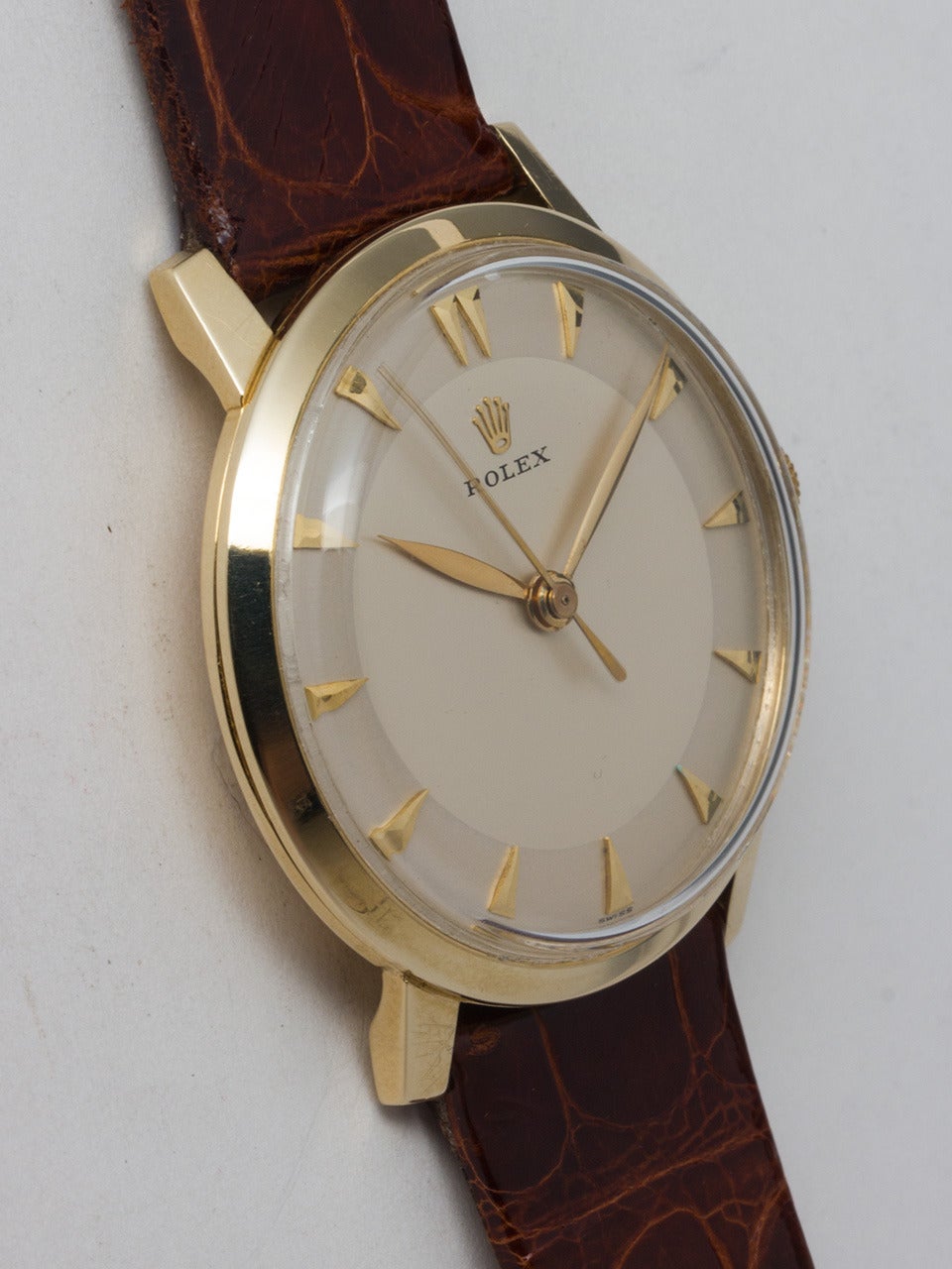 Rolex 14K Yellow Gold Dress Wristwatch, circa 1950s. 34mm case with smooth bezel and acrylic crystal. Lovely original two-tone silvered dial with applied gold arrow markers and hands. Powered by a manual-wind caliber 1215 movement. Offered on your