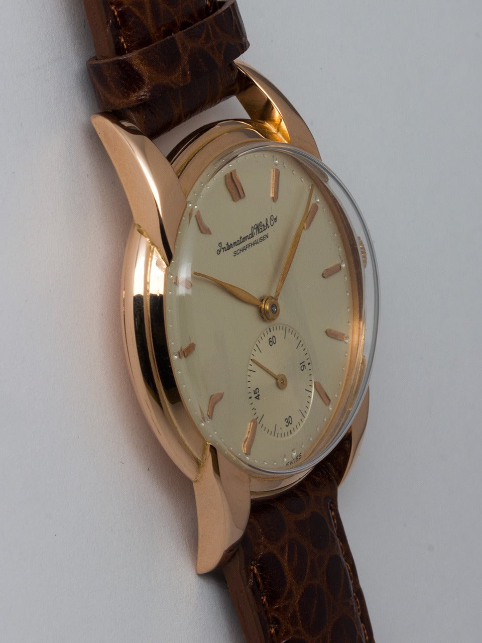 IWC 18K Rose Gold Dress Wristwatch, circa 1950s. Oversized 36.5 x 45.5mm case with fancy claw lugs. Very pleasing silvered satin dial with applied pink indexes and pink leaf-style hands. Powered by a 17-jewel manual-wind movement with subsidiary