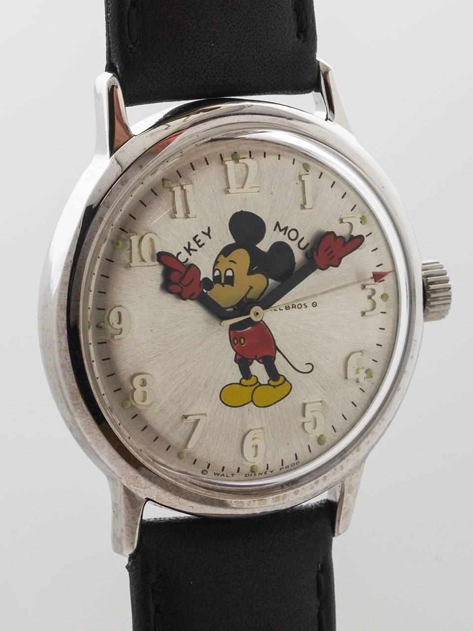 Adult-sized Helbros stainless steel and base metal Mickey Mouse wristwatch, circa 1970s. 34 x 40mm screw back case with acrylic crystal.   Silver satin dial with raised Arabic numbers, colorful image of Mickey with animated red gloved hands. Dial