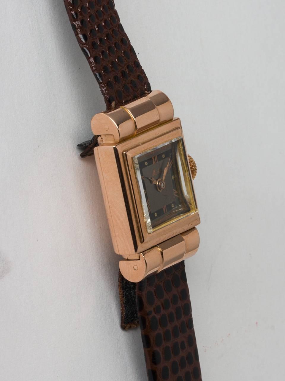 Mido 18K Rose Gold Lady’s Square Dress Model circa 1940s. 15.5 x 25mm square stepped case with barrel lugs and acrylic crystal.Lovely grey and black dial with printed pink roman numerals and applied hands. Powered by manual wind movement. Offered on