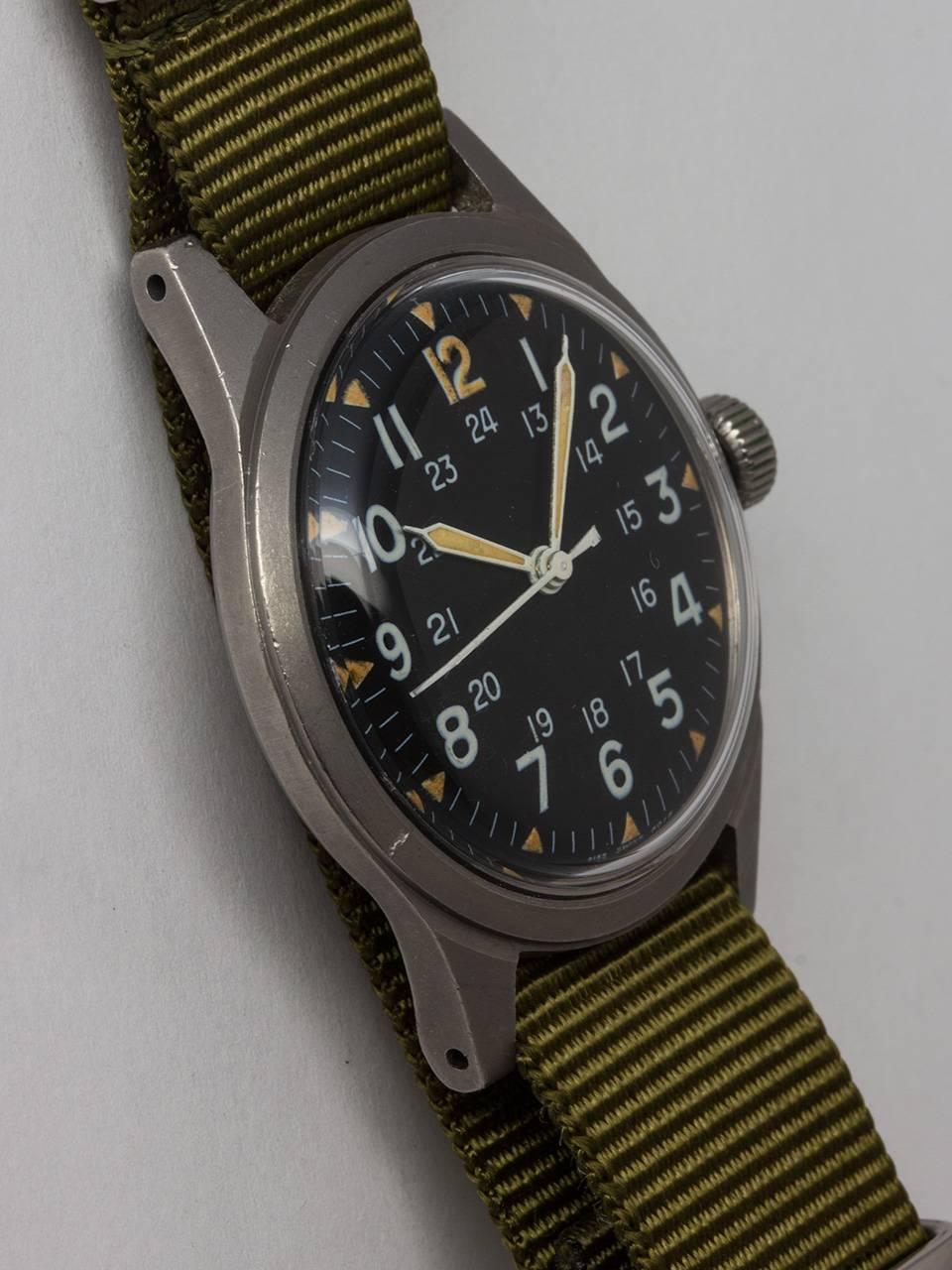 Hamilton US Military Issue Vietnam Era Wristwatch c. 1975. Featuring 34 x 41mm non reflective brushed finish base metal case and acrylic crystal. Original matte black dial with 24 hour indexes and triangular luminous hour indexes, luminous hands and