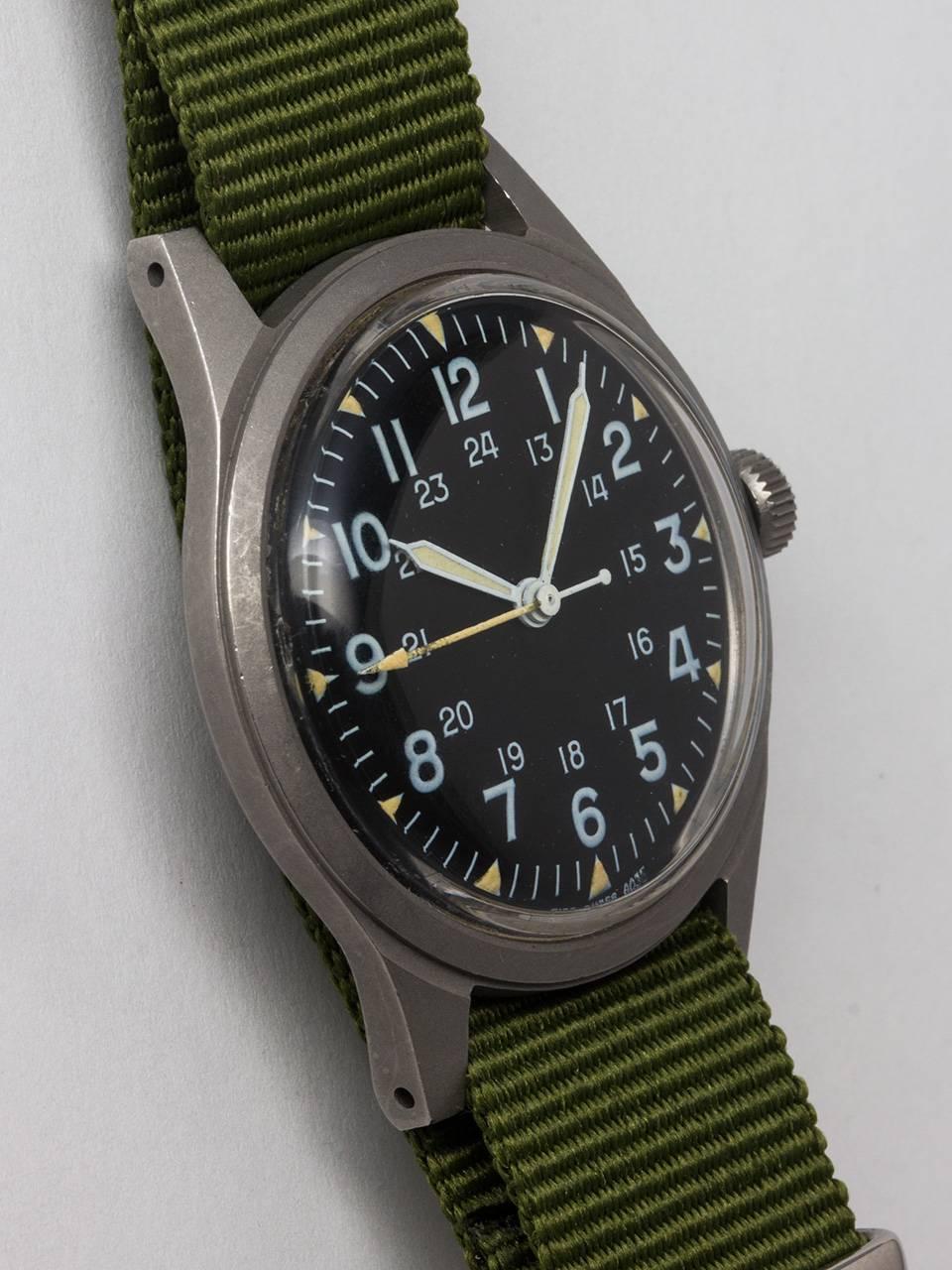 Hamilton US Military Issue Vietnam Era Wristwatch c. 1971. Featuring 34 x 41mm non reflective brushed finish base metal case and acrylic crystal. Original matte black dial with 24 hour indexes and triangular luminous hour indexes, luminous hands and