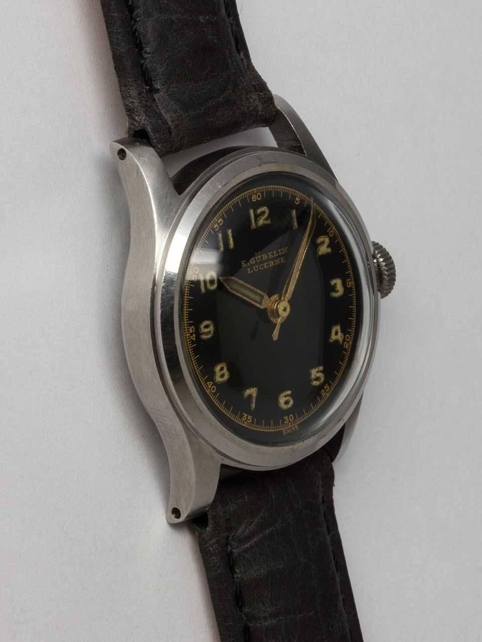 Gubelin Stainless Steel Military Style Wristwatch circa 1940s. Small case measuring 29 x 34mm diameter. Original glossy black dial with gilt printing, patina'd luminous Arabic indexes and luminous pencil hands. Powered by 17 jewel manual wind