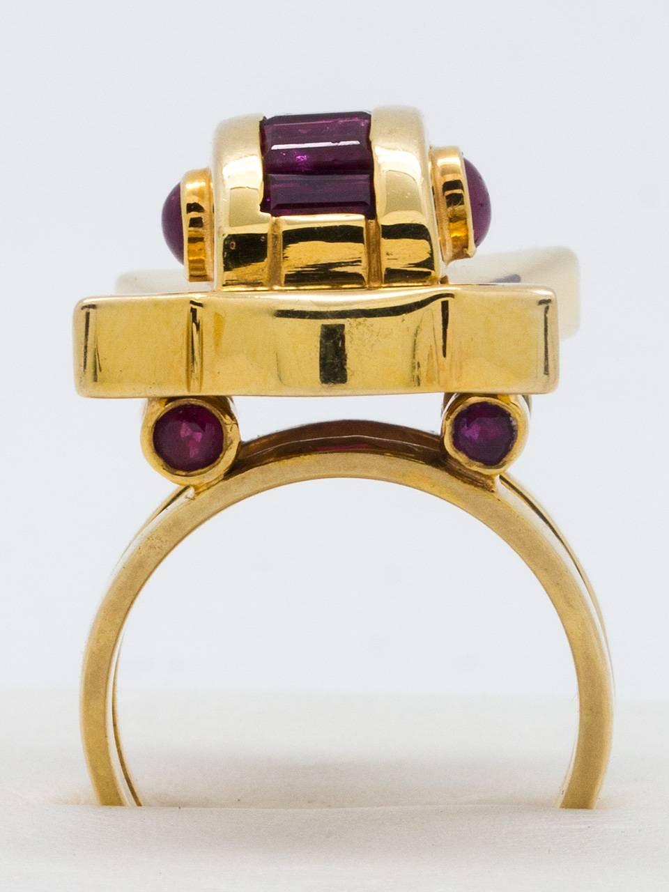 Retro style 14K yellow gold ring circa 1940’s. Great architectural style featuring bow shaped design topped with dome shaped design with calibrate ruby color stones. Accented with additional cabochon ruby colored stones. Stones of unknown origin.