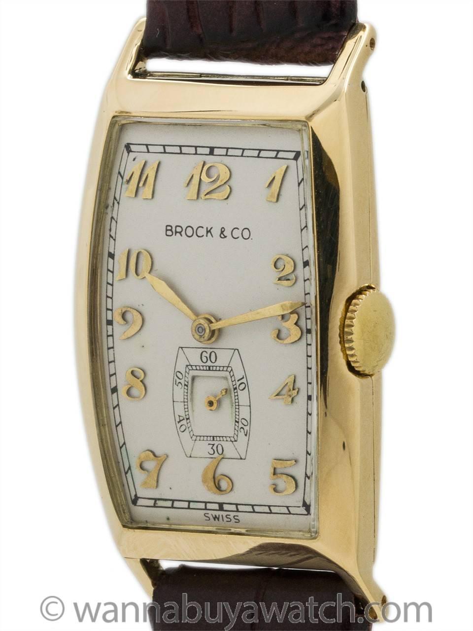 Tonneau shaped man’s gold wristwatch retailed by Brock & Co circa 1940’s. Featuring 20 x 40mm tonneau shaped case with curved mineral glass crystal, nicely restored antique white dial with gold raised arabic indexes and gilt hands. Powered by 17