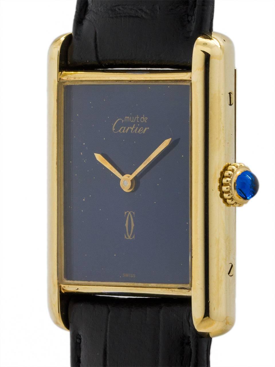 Cartier Man’s Tank Louis vermeil circa 1970s. 23.5 x 31mm case with mineral glass crystal and blue cabochon sapphire crown. With pleasing “faux” lapis blue dial signed Must de Cartier with double C logo and gold hands. The 23.5mm case width means