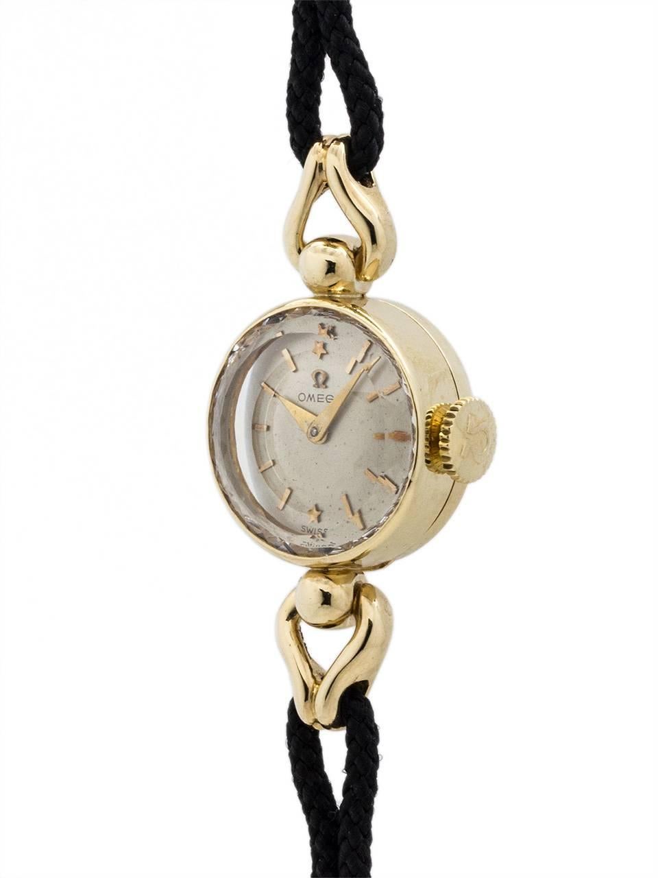 Vintage lady’s Omega 14K YG circa 1950’s. Featuring round case with elegant design ball design attachment for a nicely contoured hinge attachment for cord bracelet. Featuring a diamond cut mineral glass crystal, original silvered satin dial with