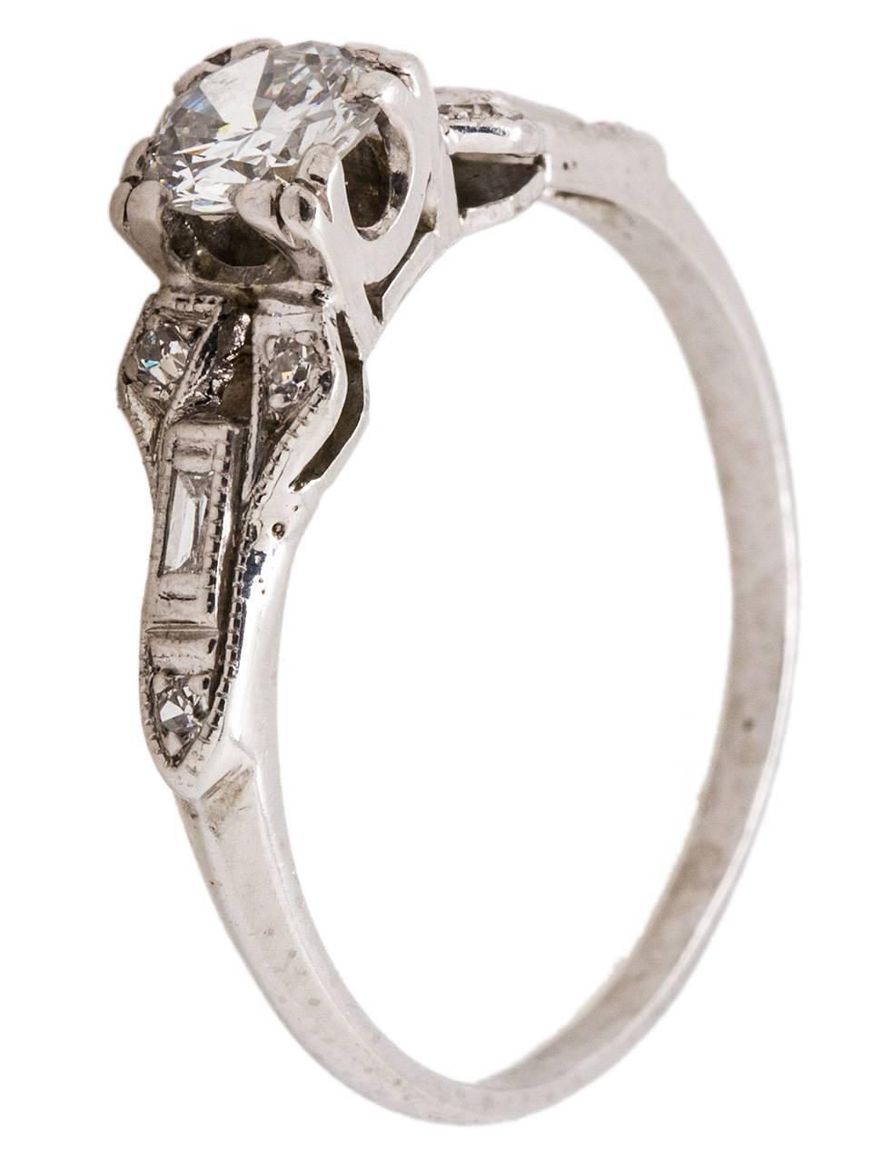This lovely Art Deco platinum diamond engagement ring is set with a stunning 0.35ct transitional round cut diamond, H/SI1. The whimsical bow-tie design is accented by six single cut and two baguette side diamonds, with a total combined weight of