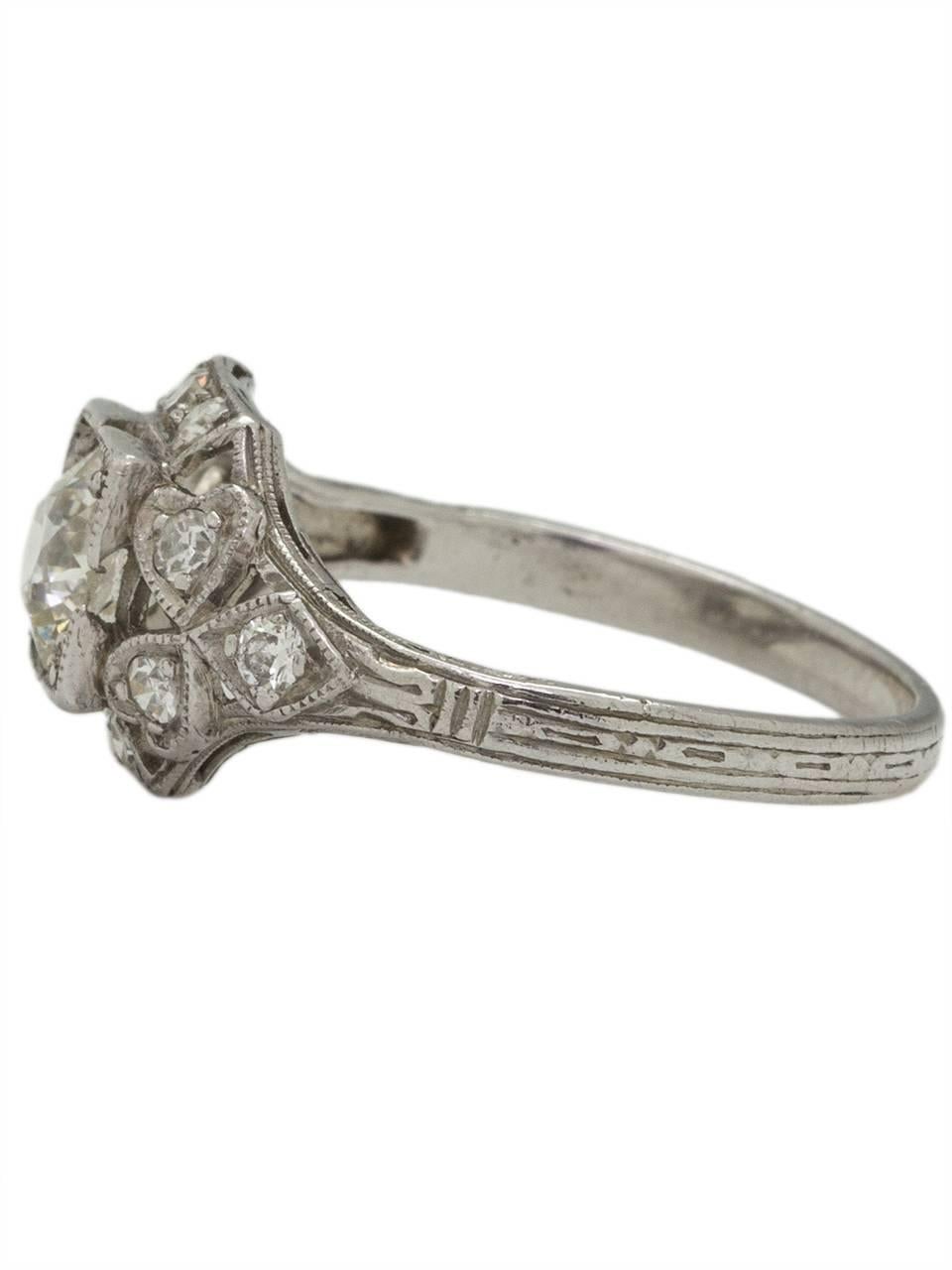 This stunning 1930s Art Deco platinum engagement ring showcases a very bright and lively EGL certified 0.75ct Old European Cut diamond, I/SI1. Twelve bead-set side diamonds which equal approximately 0.30ct are surrounded by a finely executed
