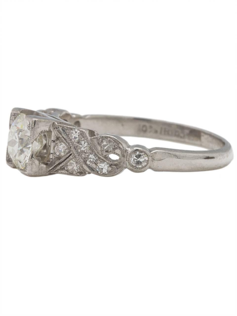 This gorgeous Art Deco antique platinum engagement ring features a beautifully cut transitional round brilliant cut center diamond weighing 0.75ct, H/SI2. The elevated square illusion set center stone setting is flanked by a lovely scrolling twist