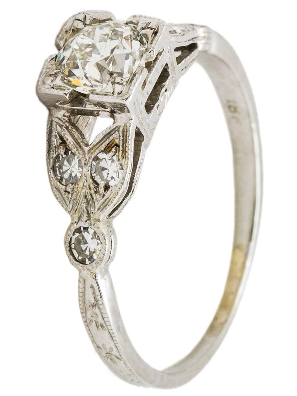 Beautifully detailed 18K white gold antique engagement ring featuring a stunning 0.48 carat old European cut diamond, I color and SI2 clarity. With six bead set side diamonds set in a floral motif, this ring would be stunning paired wit one of our