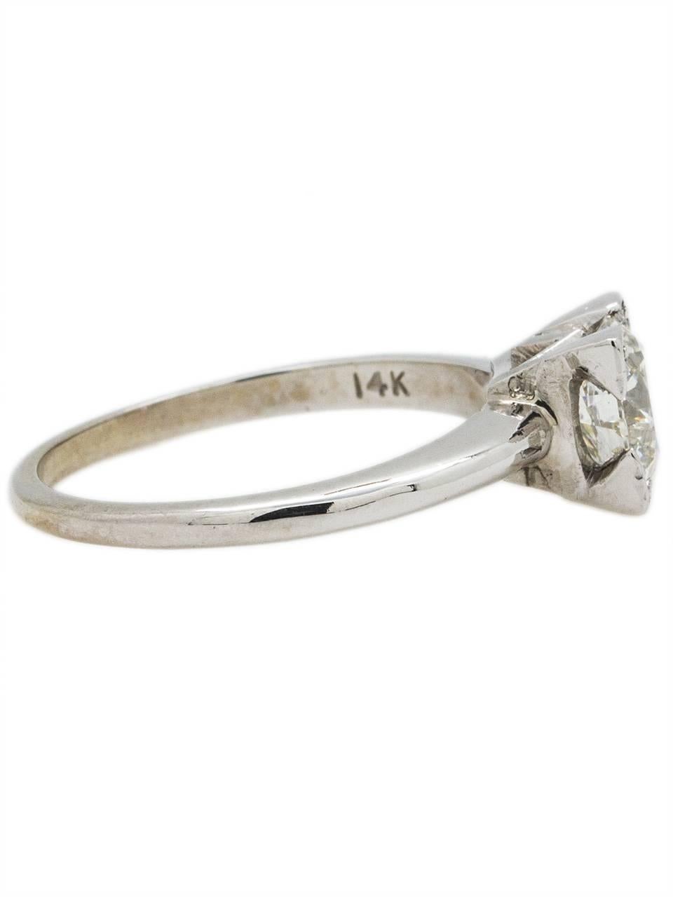 This classic 1950's 14K white gold engagement ring is set with a stunningly bright EGL certified 1.23ct Transitional Cut round diamond, G-SI2. The center stone is flanked by two bar set straight baguettes and two bead set full cut round side