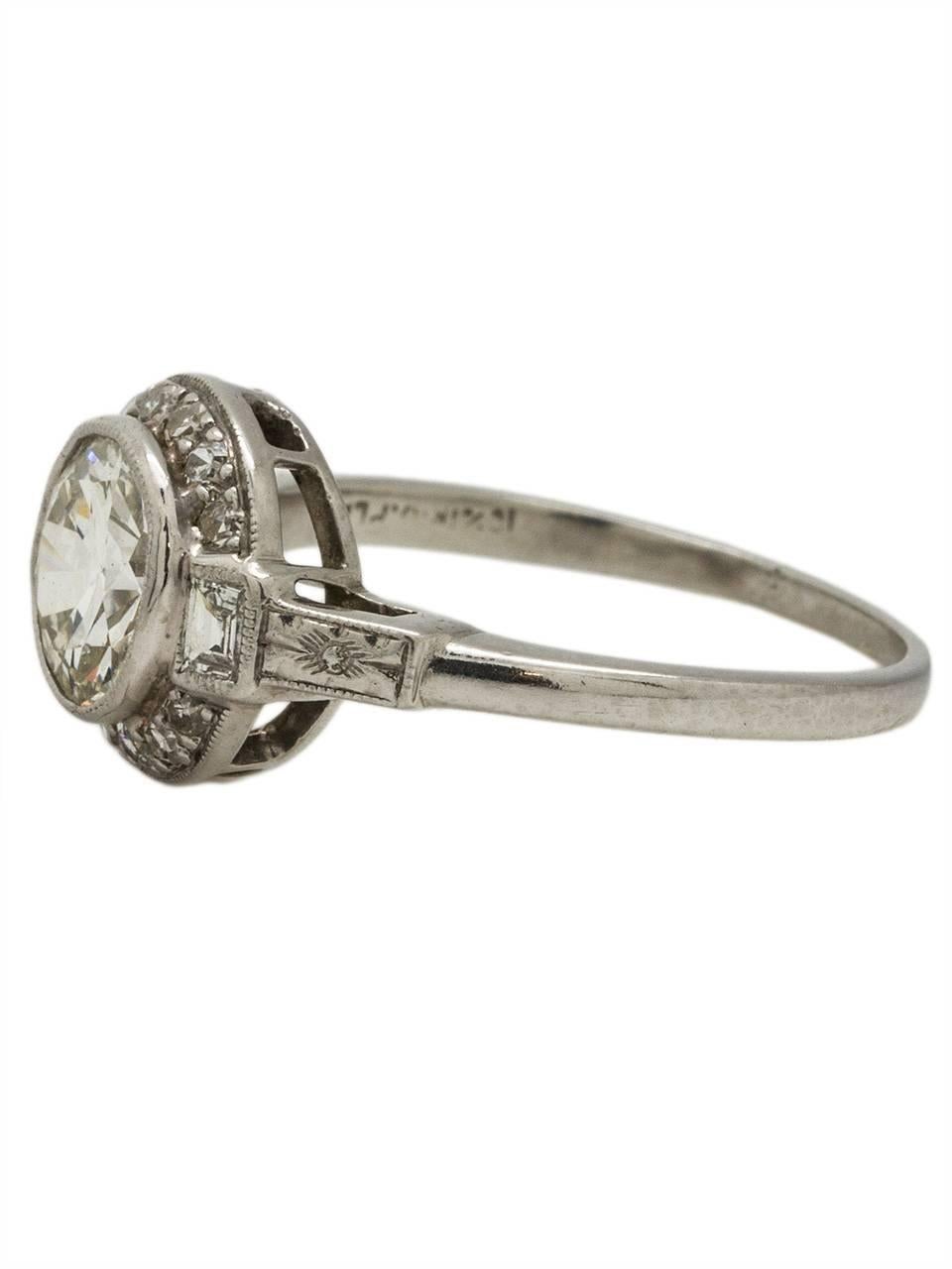 This gorgeous vintage Art Deco platinum engagement ring showcases a stunning EGL certified 1.12ct Old European Cut center diamond, H/VS1. The bezel set center stone is accented by 12 single cut and two baguette side diamonds, which add an additional