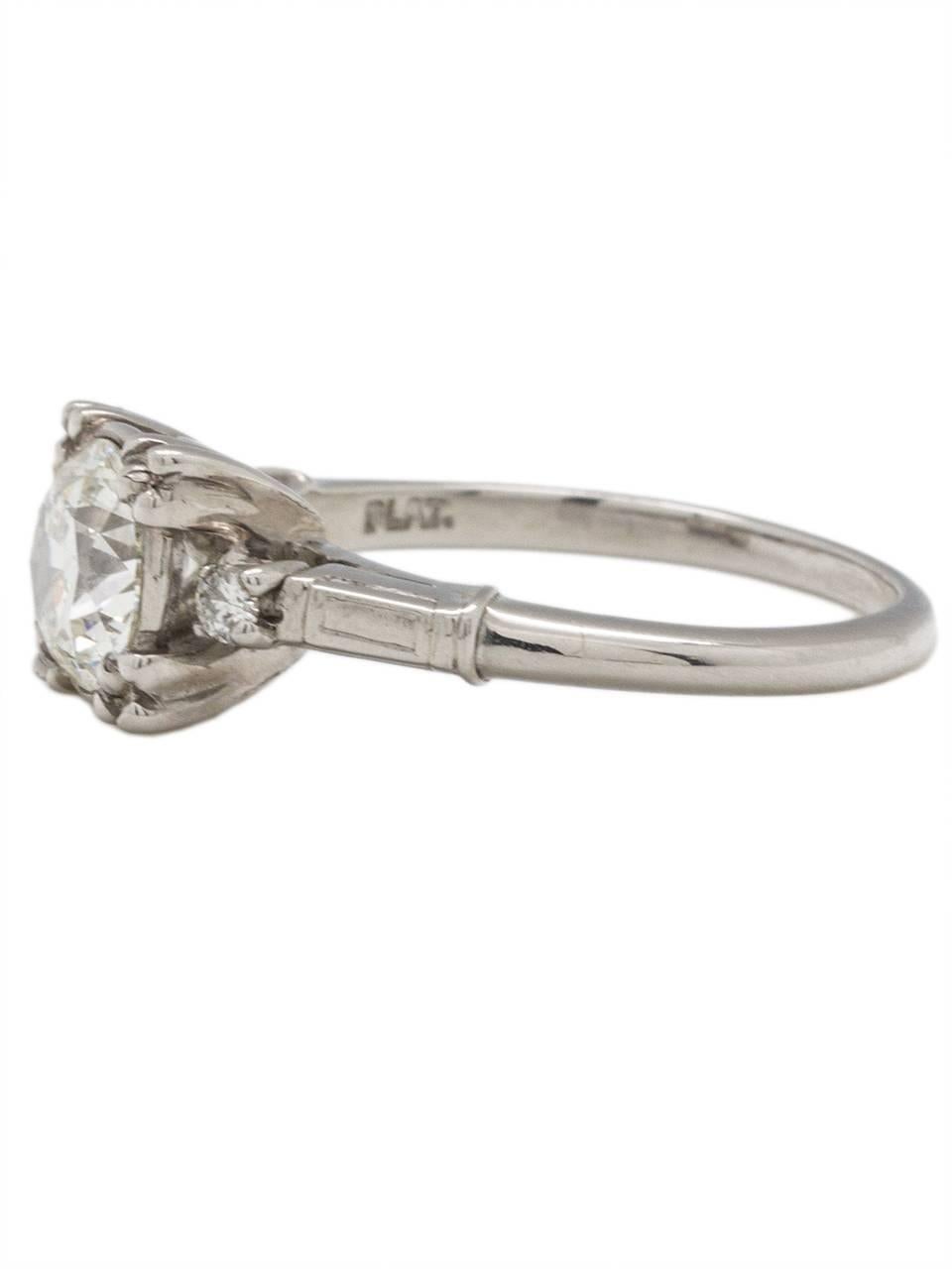 This impressive 1950s vintage platinum engagement ring features a stunningly bright 1.17 carat transitional round brilliant cut center diamond, I-VS2. Two petite round prong set side stones are the perfect accent to the center's brilliance. With an