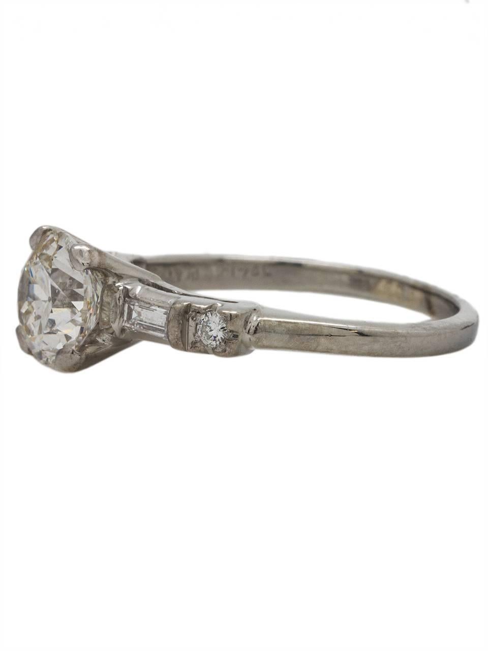 This classic 1950's 14K white gold engagement ring is set with a stunningly bright EGL certified 1.23ct Transitional Cut round diamond, G-SI2. The center stone is flanked by two bar set straight baguettes and two bead set full cut round side