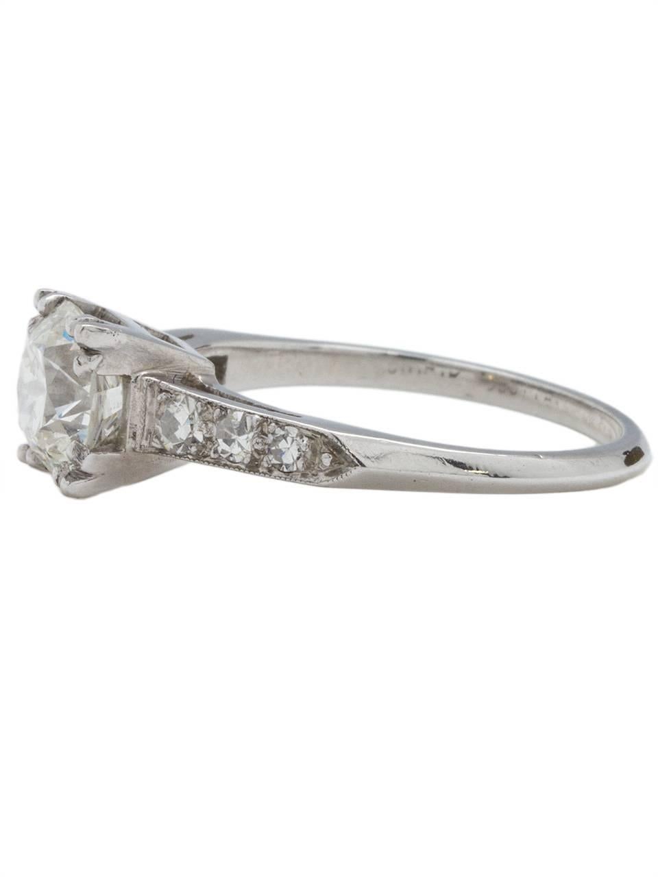 This beautiful 1940s platinum engagement ring showcases a bright and lively 1.27ct transitional Cut center diamond, H-VS1. An angular, simple channel set design is accented by six sizable single cut side diamonds, bead set with milgrain edge. Open