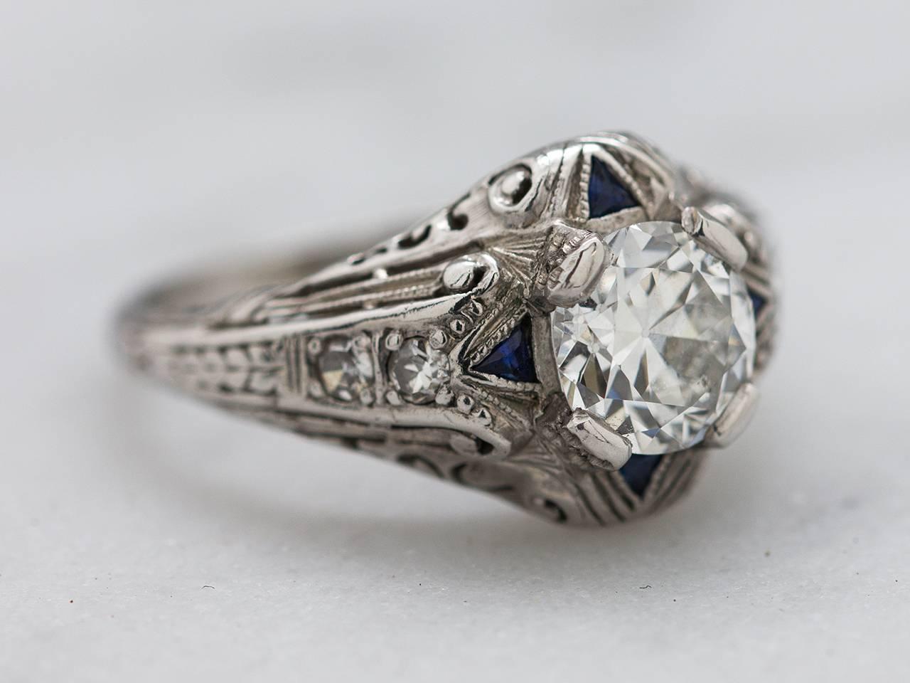 Finely crafted vintage platinum engagement ring with sapphire & diamond accents featuring an EGL certified  colorless 0.89ct Old European cut diamond E-SI2. Romantic pierced, scrolled design and finely executed hand engraved details. Absolutely