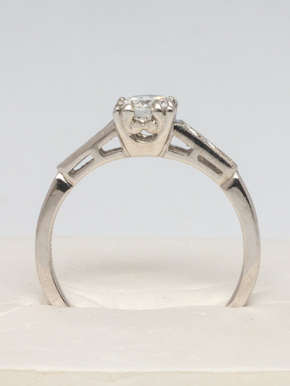 Gorgeous platinum engagement ring featuring a stunning transitional cut diamond, approximately 0.50carat, G color and VS1 clarity. Two single cut diamonds on either side, channel set with mil grain detail. Center stone measures approximately 5mm