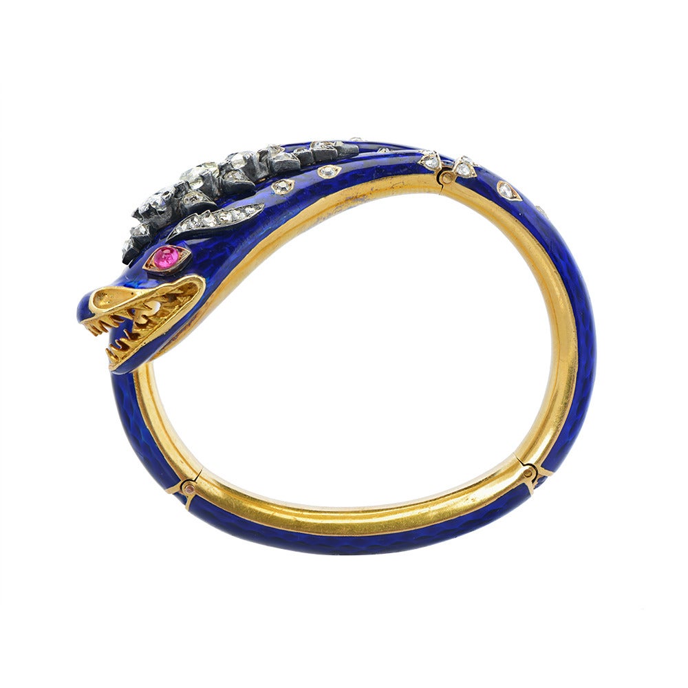 A sprung bangle of blue guilloché enamel, the head with graduated old pear-shaped and old brilliant-cut diamond crest and cabochon pink sapphire eyes, the neck and tail with further rose-cut diamond accents, circa 1850.