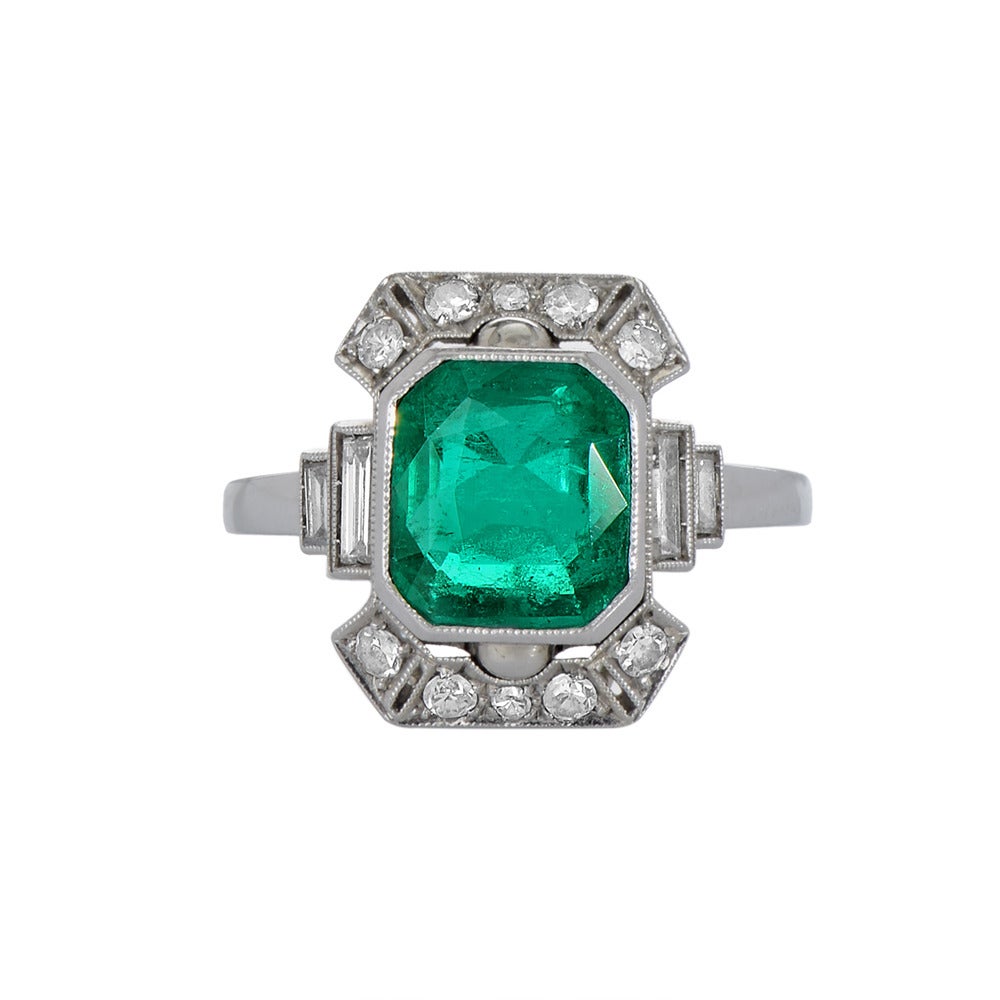 An Art Deco platinum, emerald and diamond ring, the central stone a Colombian emerald of good colour. The geometric, openwork mount set with 0.3 cts of baguette-cut diamonds and 0.26cts of rounds. Circa 1920s.

Accompanied by GCS report number