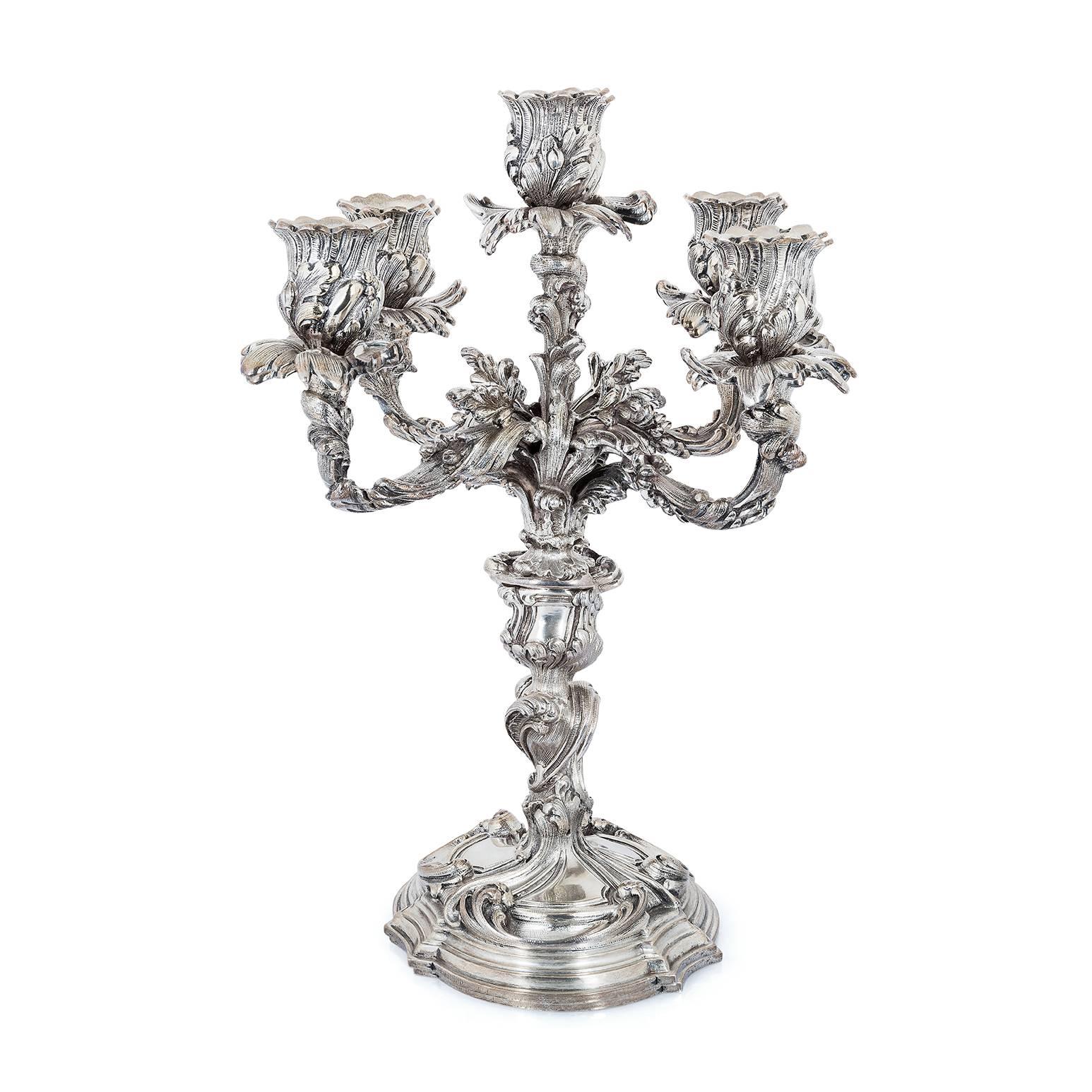 A pair of silver five light candelabra by Buccellati, in rococo style, each on a stepped circular-shaped base supporting a baluster-form shaft with applied foliate scrolls, the five branches enveloped with textured leaves, each branch supporting a