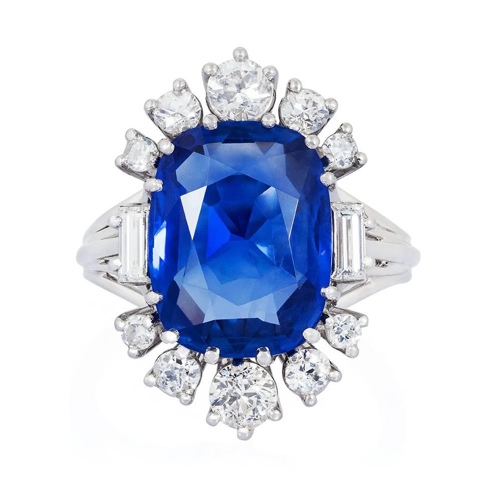 A platinum, sapphire and diamond ring, centred on an oval-shaped sapphire in a surround of claw-set round-cut and baguette-cut diamonds, to open tapered shoulders and a grooved shank. The sapphire is calculated to weigh 5.55 cts approx. Ring size 6½