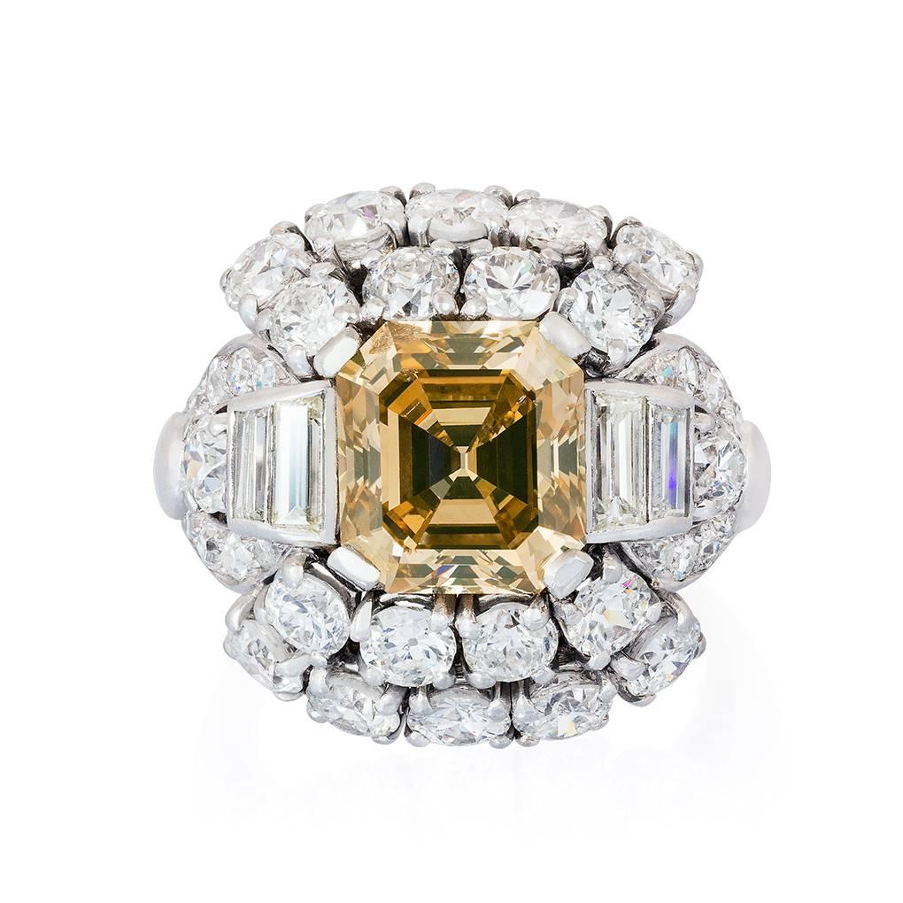 Ein cognacfarbener Ring aus Platin mit einem Asscher-Diamanten. Der 3,34-karätige Asscher-Diamant ist zwischen leicht abgestuften Schultern aus Baguette-Diamanten in einer Bombé-Umrandung aus runden Diamanten eingefasst. 