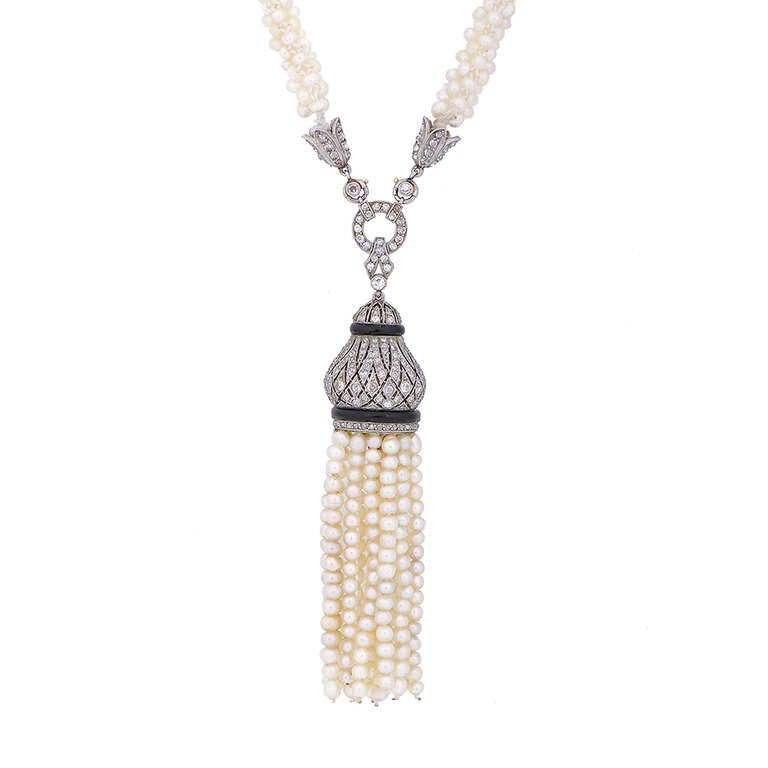 A rare Belle Epoque seed pearl necklace, plaited with natural pearls joining a diamond pavé-set clasp to the front in a lotus flower motif supporting an intricate platinum and diamond openwork pavé-set crown accented with onyx and tasselled with