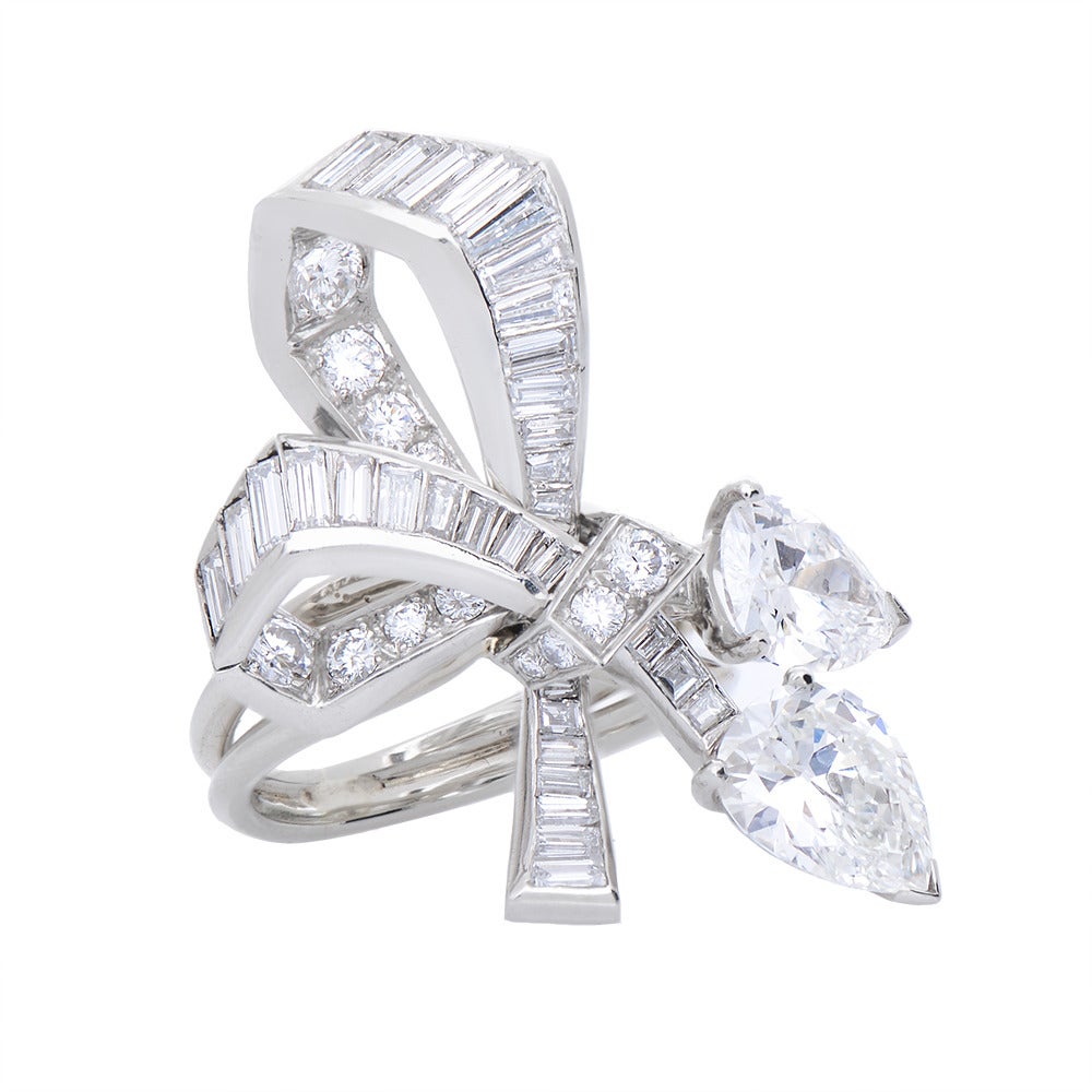 A Fine Platinum & Diamond Ribbon Bow Ring, circa 1950, the platinum bow set with graduated brilliant-cut & baguette diamonds terminating with a pair of three claw-set pear-shaped diamonds, stated to weigh 1.37cts & 1.25cts, on an open two-row shank,