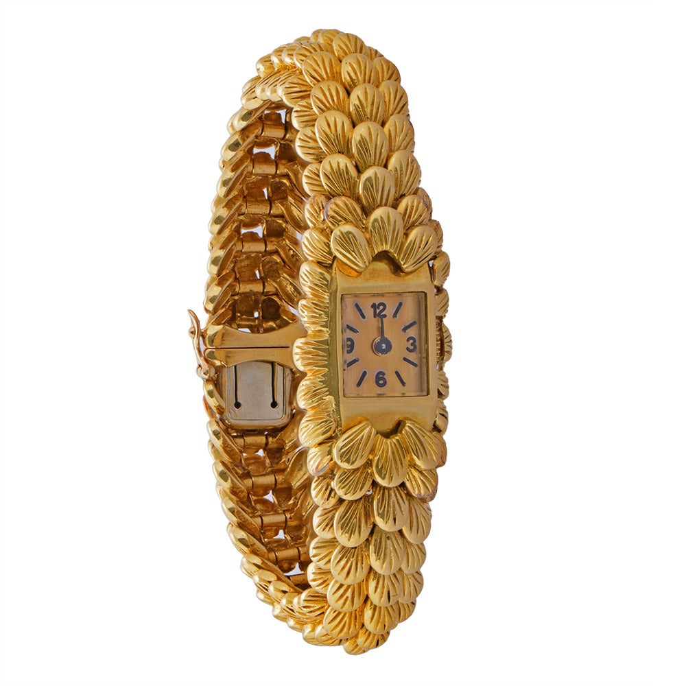A gold watch with integrated bracelet by Boucheron, composed of articulated links of textured gold leaf motif to a concealed clasp. Stamped with French assay marks for 18K gold and signed Boucheron Paris. 17cm in length and 62.42g. Circa 1960.