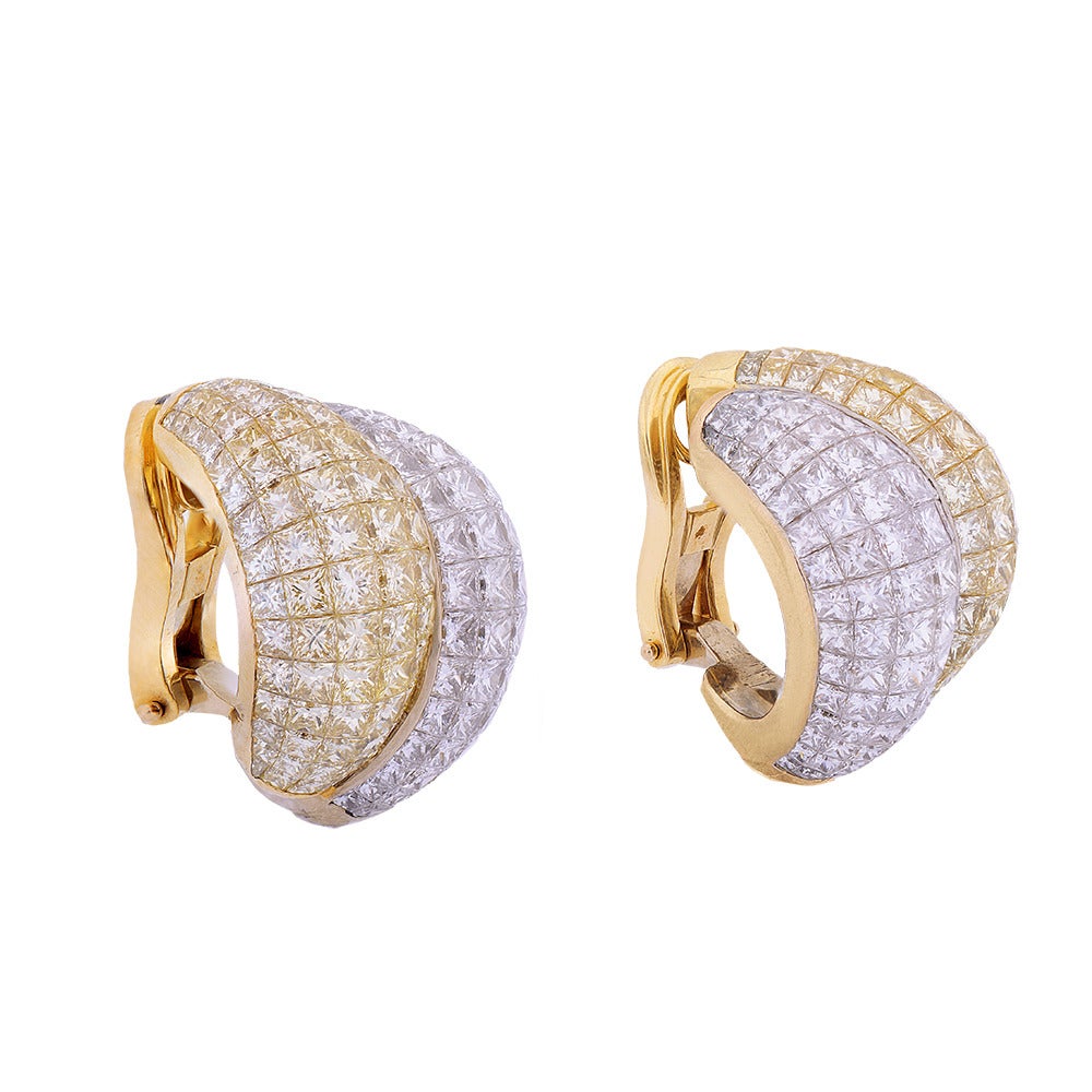A pair of split bombe diamond and gold ear clips, each composed of staggered convex bands of rose gold and yellow gold, invisibly set with 21.36cts of white and fancy-yellow, princess-cut diamonds. Contemporary.