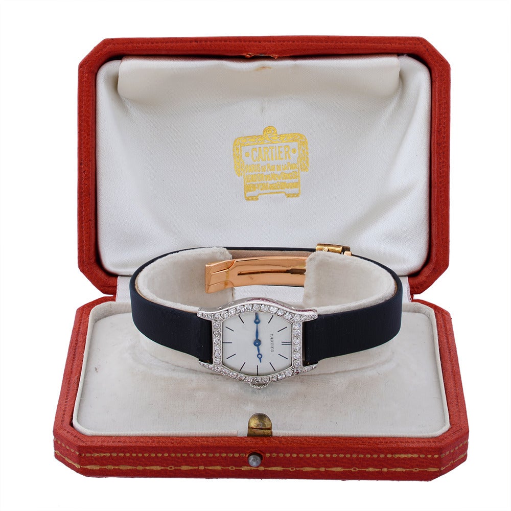 A Platinum Diamond Lady's wristwatch by Cartier with tonneau-shaped platinum case, with a gold rear and single-cut diamond-set bezel, the crown set with a single rose-cut diamond and the baton-marked dial signed Cartier with metallic blue hour and