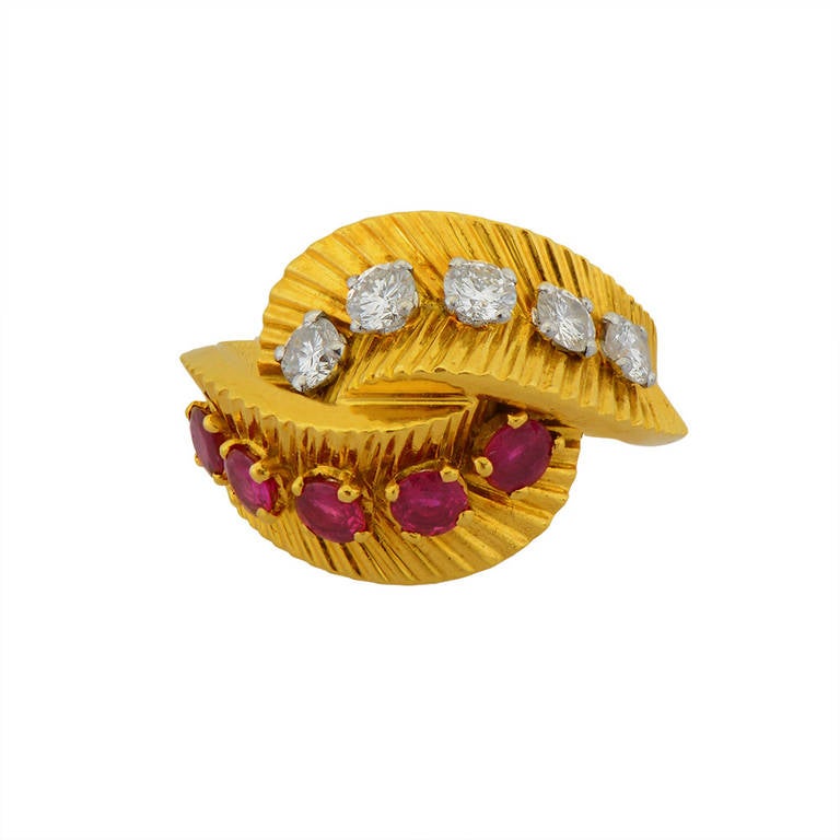 Of foliate design, the set is comprised of a brooch, a ring and a pair of earrings, set with circular-cut rubies and round brilliant diamonds ring size K, earrings with post and hinged back fittings, ring and earrings signed Van Cleef et Arpels,