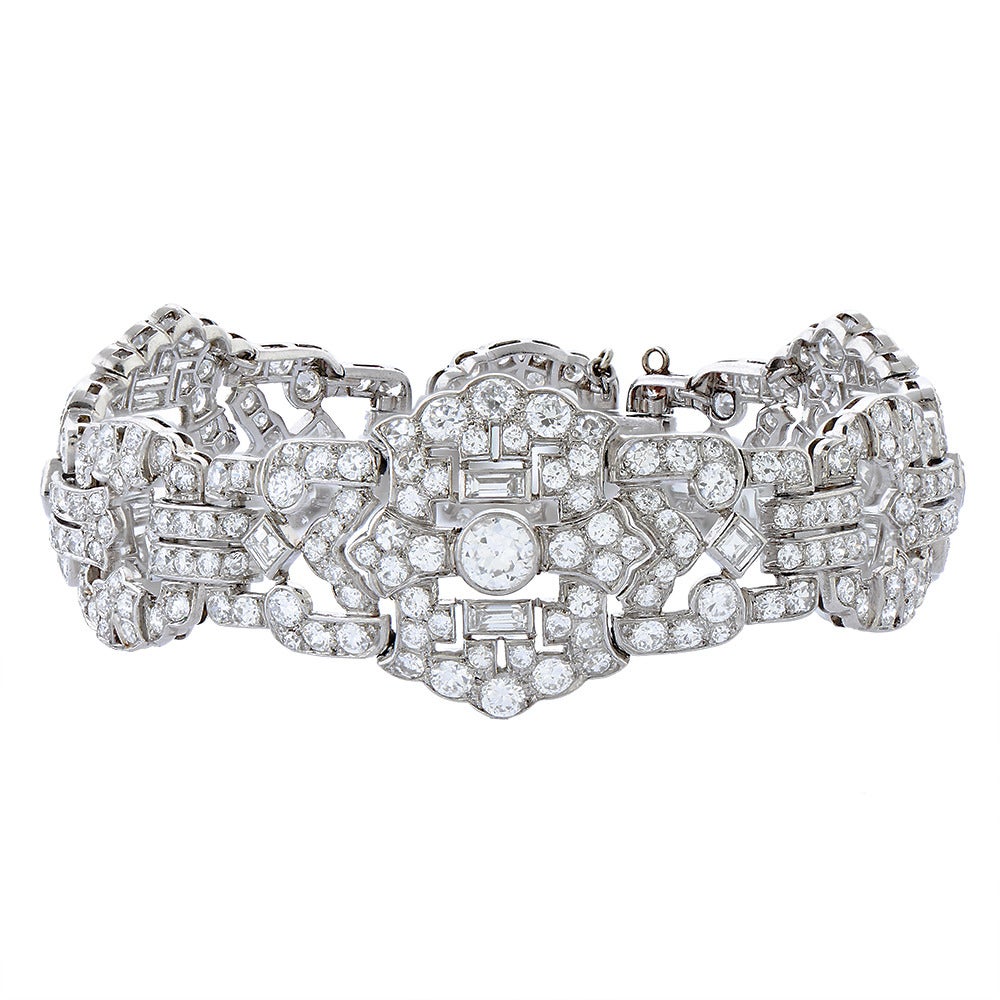 A diamond and platinum bracelet, French, composed of three panels of floral motif spaced with three openwork links to a concealed clasp, set with three hundred round-cut, six square-cut and six baguette-cut diamonds with a total weight of